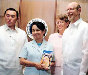 Dr. Bruce Fife presents a copy of his book 'Coconut Cures' to Philippine president Gloria Macapagal-Arroyo. Fife was honored for helping to revive the vital coconut industry in the country. 