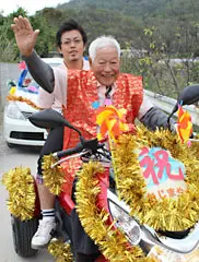 An Okinawan man joins a parade on his motorcycle as part of a celebration of his 96th birthday. 