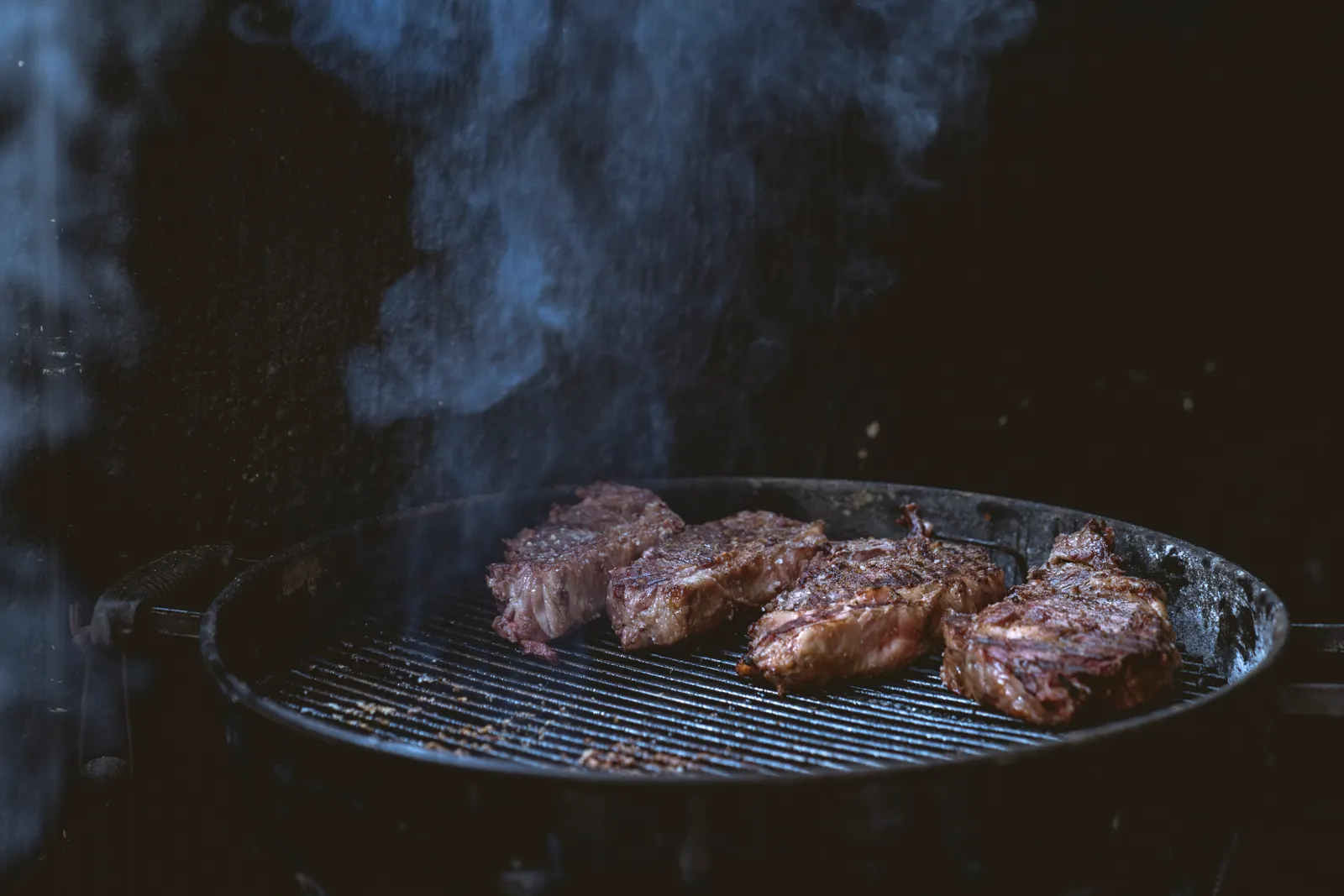 Steaks over a smoking grill